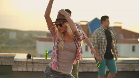 A-young-girl-beautifully-moves-her-arms-and-body-in-a-dance-on-the-roof.-Her-hair-and-shirt-are-developing-in-the-wind.-She-is-dancing-and-enjoying-with-her-friends-on-the-party.